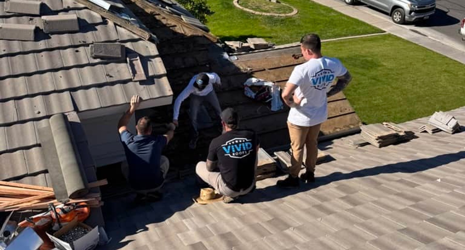 Roofing crew installing dark metal panels on roof